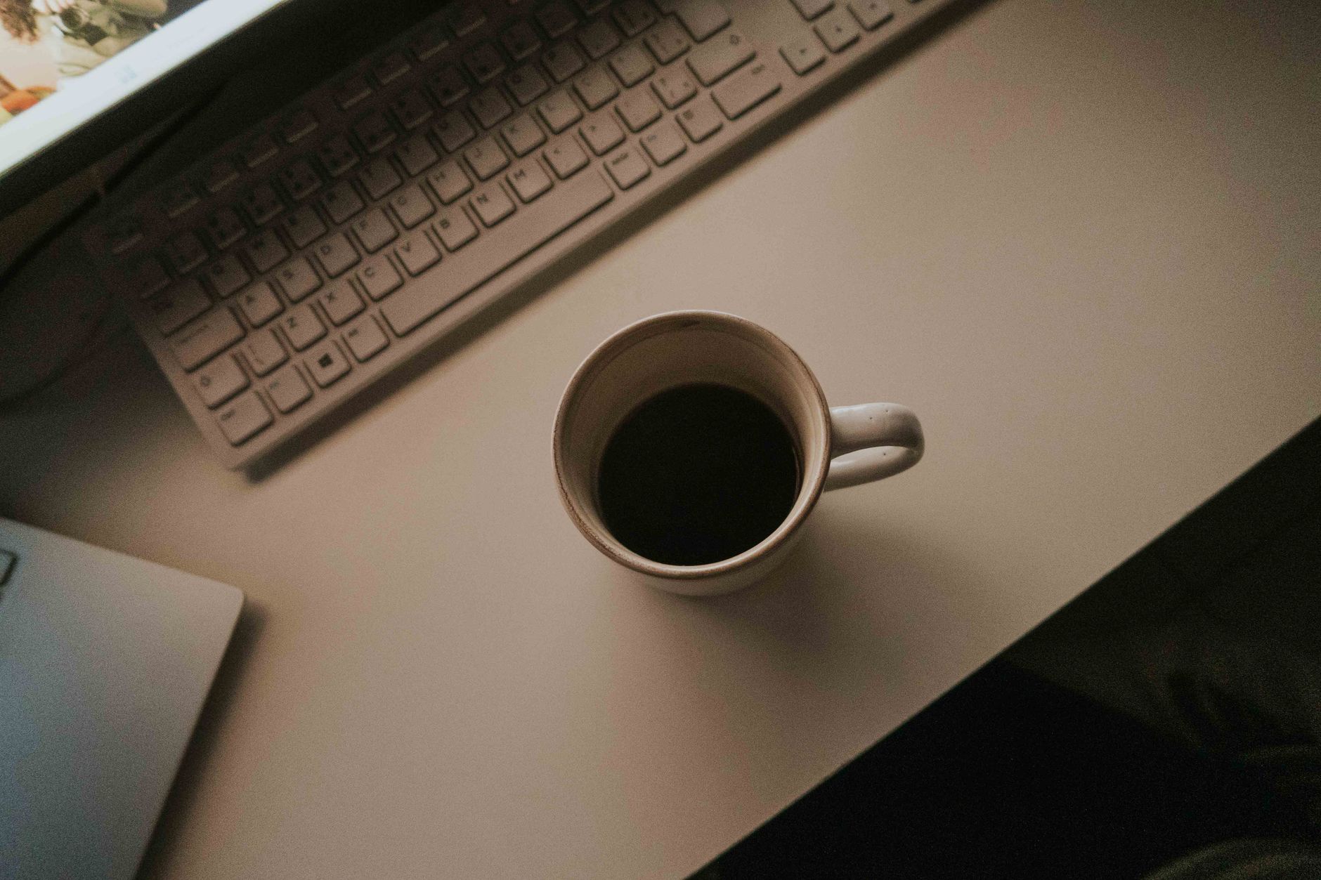 Een warm bureau met een koffiemok, toetsenbord en laptop