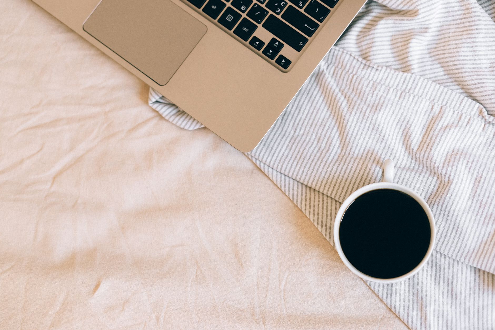 Bovenaanzicht van een laptop en koffie op een gestreepte deken