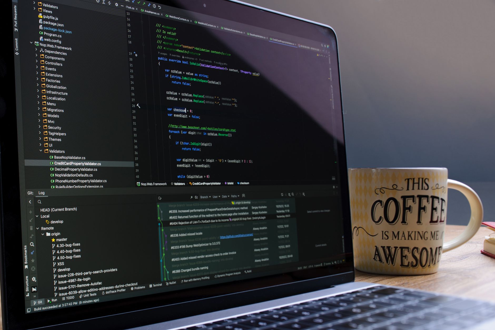Close-up van een laptop met code op het scherm en een koffiemok